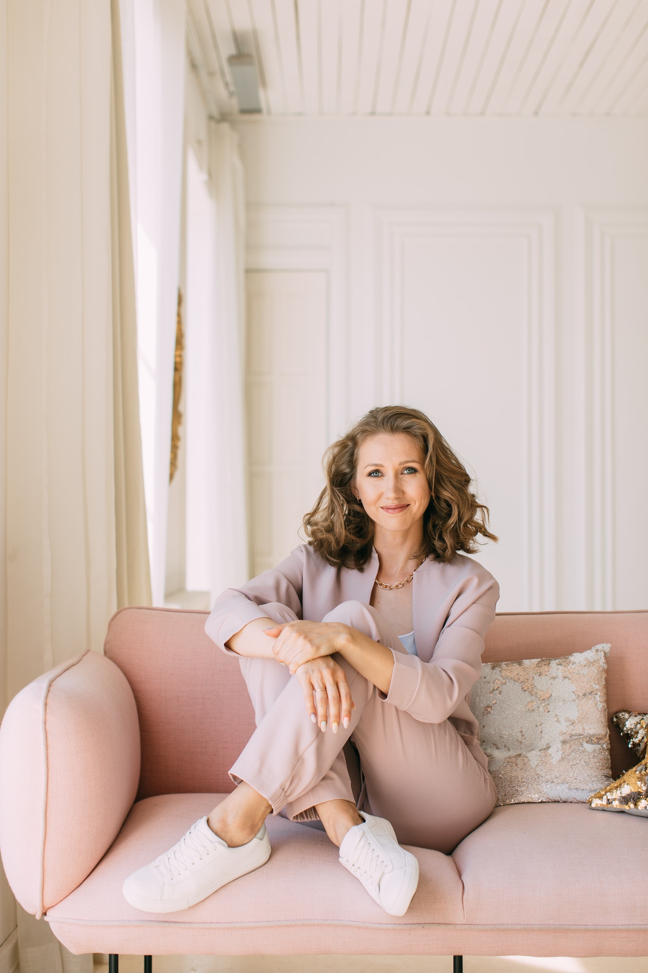 woman-sitting-on-a-pink-sofa-in-a-sun-drenched-room-and-looking-at-the-camera.jpg