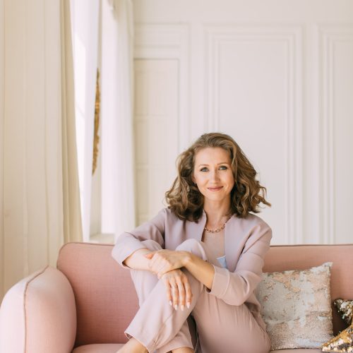 woman-sitting-on-a-pink-sofa-in-a-sun-drenched-room-and-looking-at-the-camera.jpg